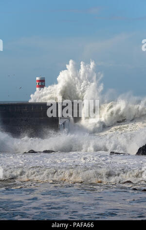 Big Stormy Sea Wave gegen Pier und Leuchtfeuer in einer schönen sonnigen Morgen. Mündung des Douro, Porto, Portugal. Stockfoto