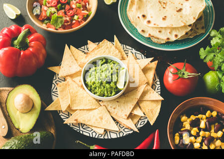 Mexikanisches Essen auswahl Guacamole Salsa Nachos Bohnen auf Schwarz konkreten Hintergrund. Ansicht von oben, getönten Bild Stockfoto