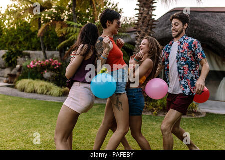 Gruppe von Freunden spielen Balloon popping Rennen an der Partei. Männer und Frauen versuchen, den Ballon jedes Anderen platzen. Stockfoto