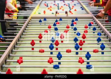Tischfußball spielen, Fußball close-up und Hände der Menschen, selektive konzentrieren. Fußball Tabelle mit roten und blauen Kunststoff Spieler, Tischfußball Stockfoto