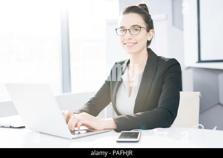 Erfolgreiche Geschäftsfrau posiert am Schreibtisch Stockfoto