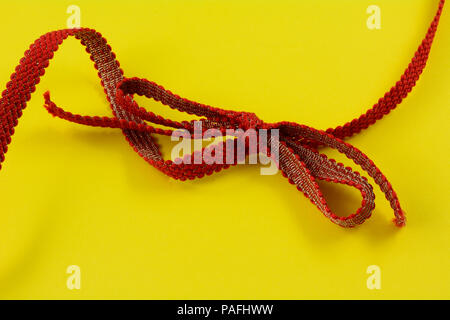 Rot und Gold Ribbon und gebunden Bogen auf gelbem Hintergrund Stockfoto
