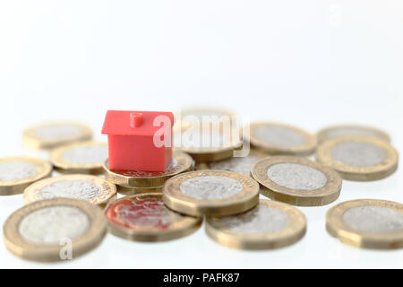 Aus rotem Kunststoff Haus auf einem Haufen neue britische Pfund Münzen. Stockfoto