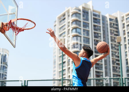 Jungen asiatischen nach dunking Basketball im Freien Gericht. Stockfoto