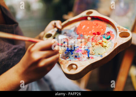 Nahaufnahme der Pinsel in der Frau die Hände mischender Farben auf palette Stockfoto