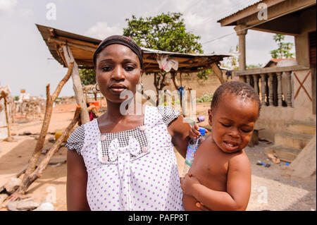 - PORTO NOVO, BENIN - Mar 8, 2012: Unbekannter beninischen Mutter trägt ihr Kind in ihren Händen Bevölkerung von Benin Leiden der Armut aufgrund der schwierigen Stockfoto