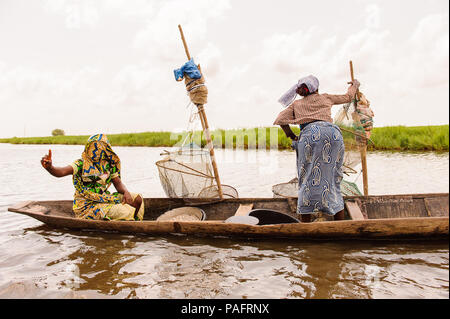 - PORTO NOVO, BENIN - Mar 9, 2012: Unbekannter Beninischen zwei Frauen Segel ein Fischerboot. Bevölkerung von Benin Leiden der Armut aufgrund der schwierigen wirtschaftlichen Stockfoto