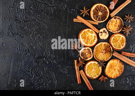 Schwarzer Hintergrund mit getrockneten Orangenscheiben, Zimtstangen und Anis Sterne Stockfoto