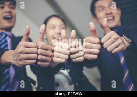 Lächelnd glücklich Unternehmer und Unternehmerinnen Erfolge feiern Erfolg Arm angehoben und Daumen zeigen oben Konzept Stockfoto