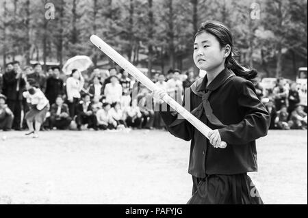 Nordkorea - Mai 1, 2012: Pioneer koreanischen Mädchen mit einem Bate spielt das Spiel durch die Feier des Internationalen Arbeiter Tag in N. Korea, 1. Mai, 2. Stockfoto