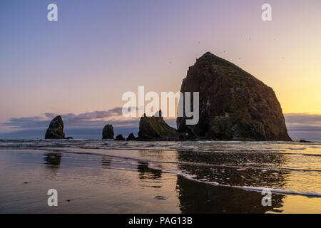 Die Haystack Rock in der Abenddämmerung, iconic natürliche Wahrzeichen der Oregon Coast, Cannon Beach, USA. Stockfoto