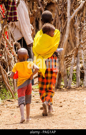 AMBOSELI, Kenia - 10. OKTOBER 2009: Unbekannter Massai Frau trägt ihr Baby auf dem Rücken tragen Tribal typische Kleidung in Kenia, Oct 10, 2009. Masse Stockfoto