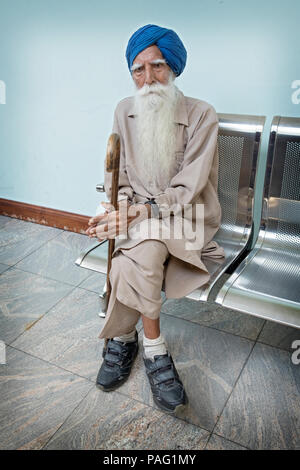 Portrait eines älteren Sikh Mann sitzt und seinen Stock Holding. In Richmond Hill, Queens, New York. Stockfoto