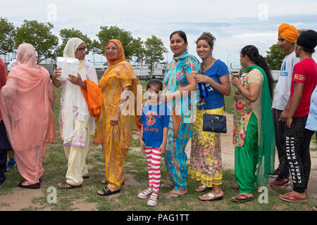 Männer, Frauen und Kinder stehen auf der Linie für Essen in der Sikh Gurmat Spiele in Smokey Park, South Richmond Hill, Queens, New York. Stockfoto