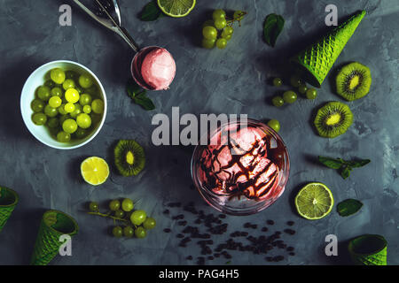 Erdbeereis mit verschiedenen Beeren und Minze auf grauem Hintergrund. Stockfoto