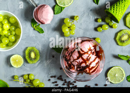 Erdbeereis mit verschiedenen Beeren und Minze auf grauem Hintergrund. Stockfoto