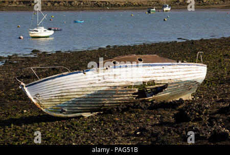 Beschädigt und Fischerboot zu Decay links am Ufer mit einem Wasser Weise im Hintergrund verlassen, Shoreline besteht aus Steinen und Felsen. T Stockfoto