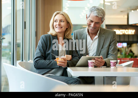Geschäftsleute, die sich mit digitalen Tablet in der Cafeteria Stockfoto