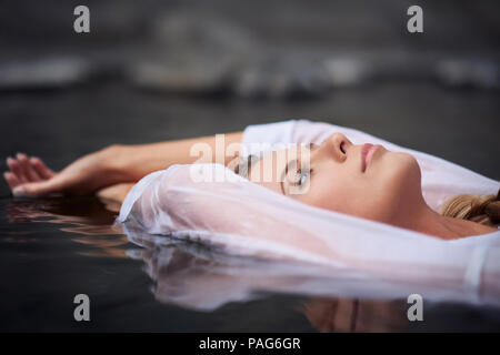 Eine tausendjährige Frau geniessen der Schönheit in der Natur beim Schwimmen in einem kleinen Mountain Creek in den Sierra Nevada Bergen in Nordkalifornien. Stockfoto