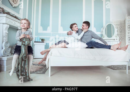 Happy Family - liebevolle Eltern und ihre Tochter auf ein hölzernes Pferd im Schlafzimmer Stockfoto