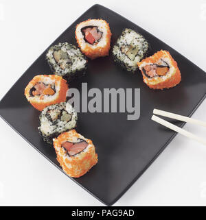 Sushi und Rollen. Der Satz ist auf schwarzem Teller serviert Stockfoto