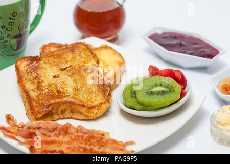 French Toast Zubereitung: French Toast gekocht und mit Obst, Schinken, Honig, Marmelade und Kaffee serviert. Stockfoto