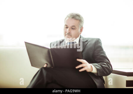 Erfolgreicher Geschäftsmann Studien Working Papers auf dem Sofa sitzen im eigenen Büro Stockfoto