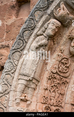 Mann mit Ketten verbindlich seinen Hals und Füße. Detail Portal der romanischen Kirche San Andrés (12. Jahrhundert) in Soto de Bureba, Provinz Burgos, Kastilien Stockfoto