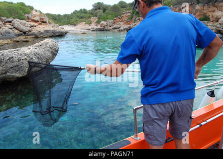 Mallorca, Spanien. 10. Juli 2018. Joan Adrover Fische in Cala Petita Bucht im Osten von Mallorca. Mehr als ein Dutzend Boote an der Küste, jeden Tag, so dass die Urlauber nicht durch die Abfälle gestört werden. Neben Kunststoff die Männer Fisch alle Arten von Kuriositäten. Quelle: Patrick Schirmer Sastre/dpa/Alamy leben Nachrichten Stockfoto