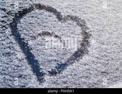 Eine Zeichnung in der Form eines Herzens auf den gefallenen Schnee auf dem Auto Glas Stockfoto