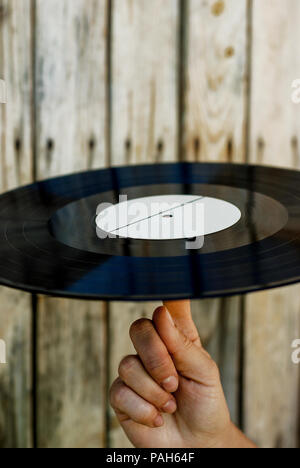 Weibliche Hand, die eine Schallplatte über Holz- Hintergrund Stockfoto