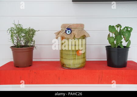 Zwei Töpfe mit Blumen auf dem Holzregal. Zwischen der Fangkörbe Glas Glas der eingemachten Gurken Stockfoto