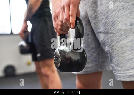 Nicht wiederzuerkennen, junge Männer in der Turnhalle tun kettlebell Schaukeln. Stockfoto