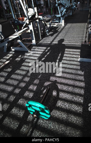 Fitnessraum mit verschiedenen Trainingsgeräten, der Schatten einer Person heraus zu arbeiten. Stockfoto