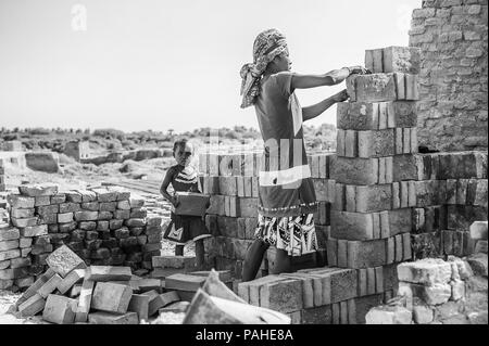 ANTANANARIVO, MADAGASKAR - Juli 3, 2011: Unbekannter Madagaskar Frau macht eine Wand aus Ziegel und ein kleines Mädchen hilft ihr. Menschen in Madagaskar leiden Stockfoto