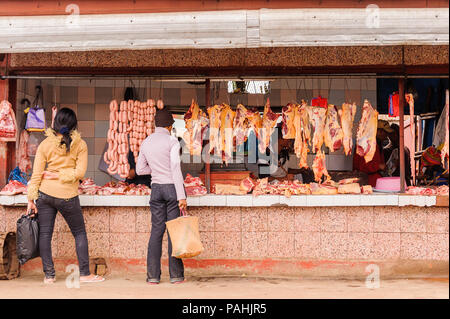 ANTANANARIVO, Madagaskar - 29. JUNI 2011: Unbekannter Madagaskar Mann wählt Fleisch- und Wurstwaren auf dem Markt. Die Menschen leiden an Armut in Madagaskar Stockfoto