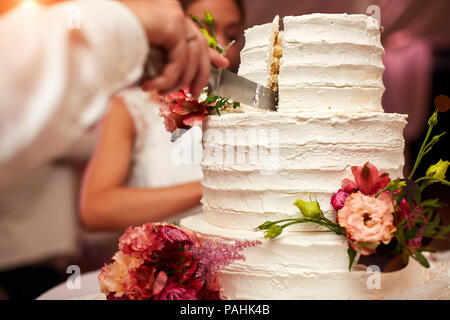 Bräutigam schneidet die Hochzeitstorte Stockfoto