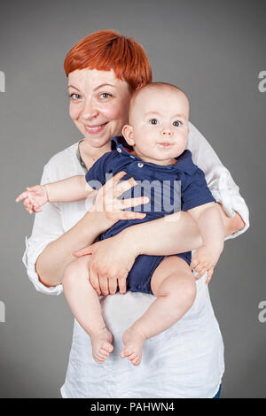 Porträt einer Mutter und lächelnd ein Sabbernder baby boy, Vertikal, auf Grau mit Vignette isoliert Stockfoto