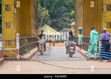 Verschiedene Leute fahren Sie über die Brücke zu Fuß und auf Motorrädern in der Republik Guinea Stockfoto