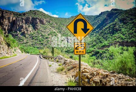 Eine Landstraße Ansicht einer Kurve voraus Schild im Vordergrund der Klippen voller sauagro Kakteen im Coronado National Forest, in der Nähe von Tucson, AZ, USA Stockfoto