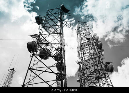Ein Blick nach oben aus einem Cluster von Telekommunikation satillite Türme gegen ein bewölkter Himmel, finsterer in Schwarz und Weiß Stockfoto