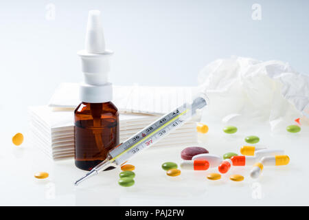 Thermometer, Pillen, braunen Flasche Nasenspray und verwendet Gewebe auf weißem Hintergrund. Erkältung und Grippe Konzept Stockfoto