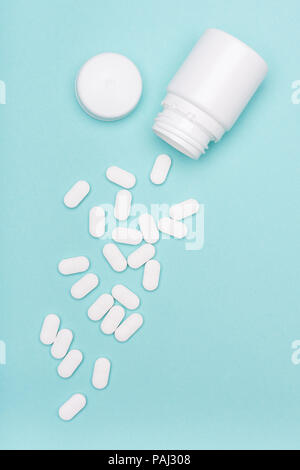Medikation Flasche und weiße Pillen auf Blau pastellfarbenen Hintergrund verschüttet. Medikamente und verschreibungspflichtige Pillen flachbild Hintergrund legen. Opioid-Epidemie. Stockfoto