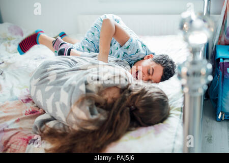Little Boy und seine ältere Schwester sind playfighting auf einem Bett zu Hause. Stockfoto