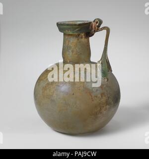 Glaskanne. Kultur: Roman. Abmessungen: 4 5/16 in. (10,9 cm) Andere: 3 5/16 in. (8,4 cm) Durchm. Von rim: 1 1/2 in. (3,9 cm). Datum: Mitte 1.-2. Jh. N.CHR.. Transluzent blau grün; in gleicher Farbe. Kragen rim ausgeklappt, nach unten und oben, mit abgerundetem äußeren vertikalen Lippe; leicht trichterförmig zylindrische Hals, mit schnittspuren an der Basis; kugelförmigen Körper; konkave Unterseite; Strap Griff in vier Kralle Pads zu schultern, erstellten und horizontal gedreht, mit einem vertikalen als Daumen oben Rim falten und dann schleppte am äußeren Rand von Rim und oben am Hals. Intakt; wenige Blasen im Körper, aber m Stockfoto