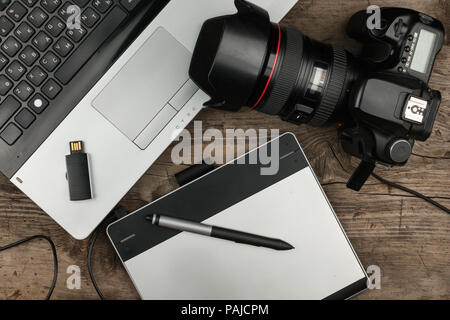 Blick von oben auf die Designer Tisch mit Laptop, Grafiktablett, Foto Kamera und Flash Drive. Fotograf frist Konzept. Stockfoto