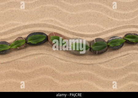 Steinen und grünes Blatt auf dem Sand mit Dünen und Wellen. Spa und Zen-Konzept. Ansicht von oben Stockfoto