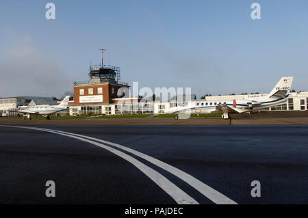 Eine Cessna 560 Citation und eine Piper PA -31-350 Navajo Häuptling auf dem Vorfeld mit dem Terminal und der Luftverkehrskontrolle geparkt - Tower hinter Stockfoto