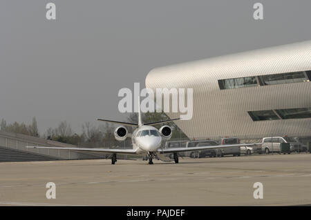 Eine Cessna Cessna Citation 560 XL Citation Excel auf dem Vorfeld mit dem TAG Aviation Terminal hinter geparkt Stockfoto