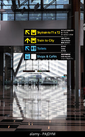 Skytrain, Züge nach Stadt, Toiletten, Geschäfte und Cafés Zeichen mit Karren hinter sich auf der oberen Ebene über MRT in Singapur Changi, Klemme 3 Stockfoto